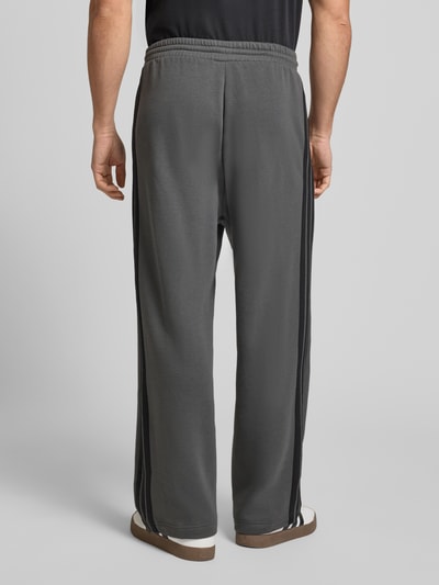 Männermodel trägt Sweatpants mit elastischem Bund und Tunnelzug von adidas Sportswear, grau, Baumwoll-Mix, Logo, Ganzkörperansicht Rückansicht.