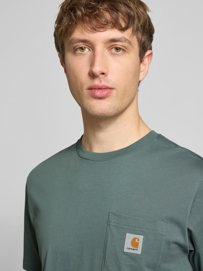 Männermodel trägt Regular Fit T-Shirt mit Logo-Patch von Carhartt Work In Progress aus reiner Baumwolle, Nahaufnahme Oberkörper.