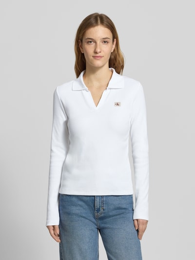 Modelka nosi Longsleeve mit Label-Detail od Calvin Klein Jeans, biały, krój slim fit, kołnierzyk polo, bawełna z elastanem, długość tyłu S: 57 cm, widok całej sylwetki z przodu.