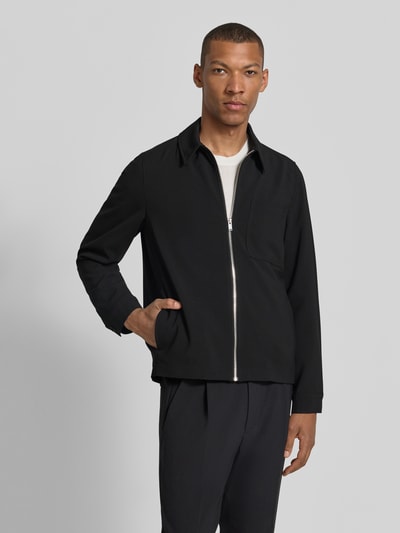 Männermodel trägt Overshirt mit Brusttasche Modell 'JERSON' von Drykorn, schwarzer Material-Mix mit Viskose-Anteil, Modern Fit, Kentkragen, Reißverschluss, Rückenlänge bei Größe M: 69 cm, Ganzkörperansicht von vorne.