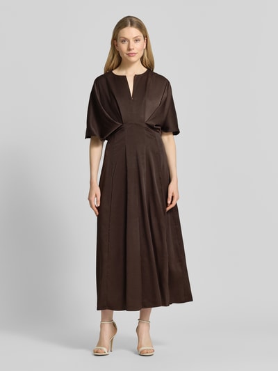 Frauenmodel trägt Midikleid mit V-Ausschnitt Modell 'VIANNA' von Copenhagen Muse in Dunkelbraun, tailliert mit Drapierungen, Ganzkörperansicht von vorne.