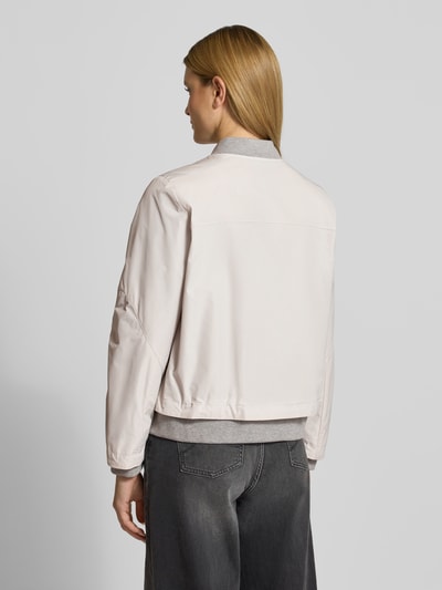 Frauenmodel trägt Bomberjacke mit Zweiwege-Reißverschluss von Amber & June in Beige, krój regular fit, Stehkragen, Szerokość w rozmiarze 36: 50 cm, długość tyłu w rozmiarze 36: 59 cm, szaro-beżowy odcień, gładka tekstura, tylna kieszeń, widoczne subtelne szwy, Ganzkörperansicht Rückansicht.