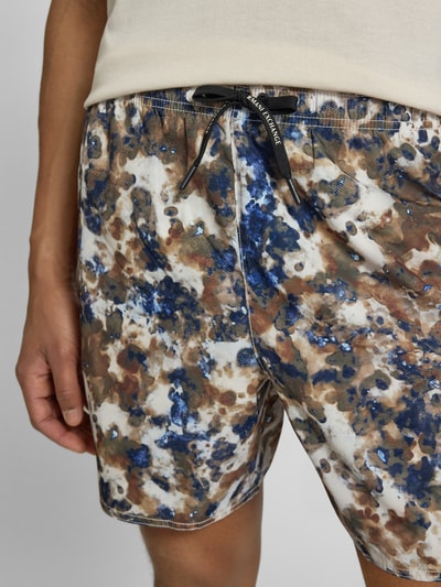 Männermodel trägt Shorts im Allover-Look mit elastischem Bund von ARMANI EXCHANGE, Regular Fit, abstraktes Farbmuster in Blau, Braun und Weiß, Nahaufnahme Oberkörper.