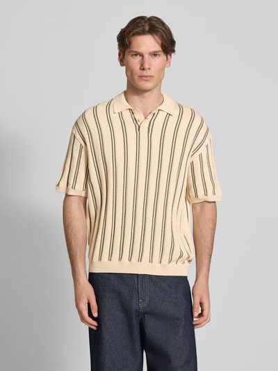 Männermodel trägt Regular Fit Strick-Poloshirt Modell 'POUL' von Redefined Rebel aus Baumwoll-Mix, creme mit dunklen Längsstreifen, Knopfleiste, Rückenlänge bei Größe M 66 cm, Ganzkörperansicht von vorne.