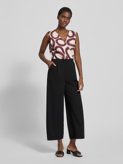 Frauenmodel trägt Jumpsuit mit Eingrifftaschen Modell 'Bi44lina' von ZABAIONE, Material-Mix mit Stretch-Anteil, weites Bein, V-Ausschnitt, schwarz-creme gemustert, Ganzkörperansicht von vorne.