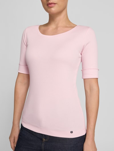 Frauenmodel trägt T-Shirt mit Rundhalsausschnitt und Label-Detail von Marc Cain aus Baumwoll-Elasthan-Mix in Slim-Fit, sanft rosa, Ärmel mit Aufschlag, Rückenlänge bei Größe 36: 55 cm, Nahaufnahme Oberkörper.