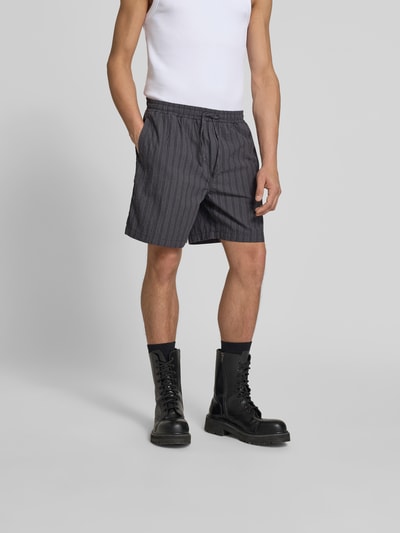Männermodel trägt Shorts mit Stretch-Anteil von Forét, grau-gestreift, Regular Fit, Baumwoll-Elasthan, elastischer Bund, Nahaufnahme Oberkörper.