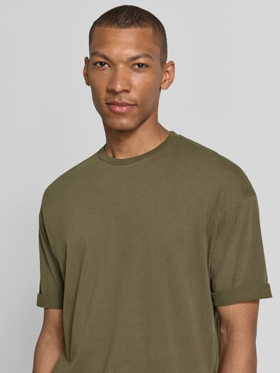 Männermodel trägt T-Shirt mit Ärmelaufschlag und Rundhalsausschnitt von Drykorn in Olive, Reine Baumwolle, Regular-Fit, Nahaufnahme Oberkörper.