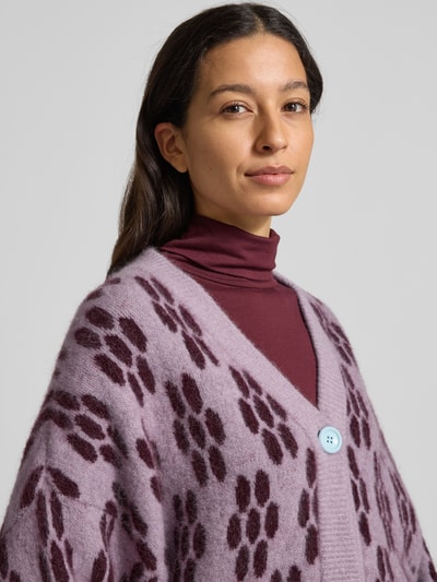 Vrouwenmodel draagt Gebreid jack met knoopsluiting Model 'VITOW' van American Vintage, mix van alpaca en lanawol met stretch, los model, ribboorden, V-hals, bordeaux en lila tinten, detailopname bovenlichaam.