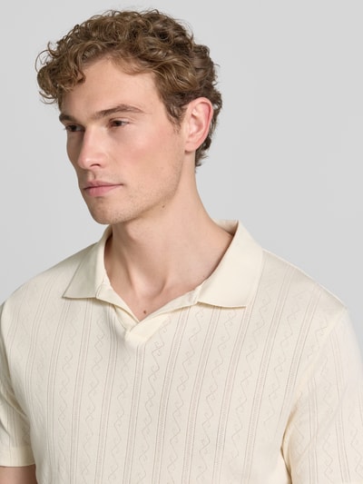 Męski model nosi Regular Fit Poloshirt in Jaquard-Strick von Lindbergh, bawełna, kołnierzyk polo, dekolt w serek, detal z logo, kremowy, dzianina żakardowa, krój regular fit, długość tyłu w rozmiarze M: 73 cm, zbliżenie na górną część ciała.