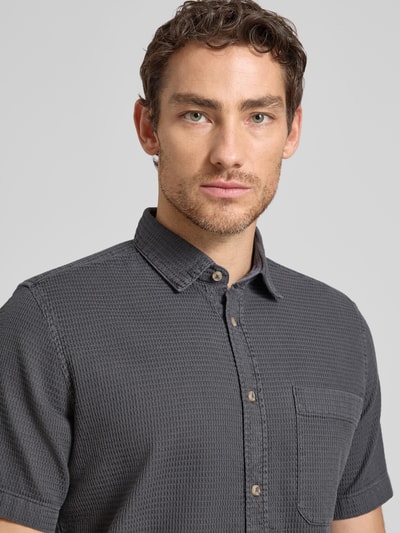 Męski model nosi Regular Fit Freizeithemd aus reiner Baumwolle od Tom Tailor, efekt: jednolity kolor, faktura, kołnierzyk typu kent, listwa guzikowa na całej długości, krótki rękaw, brustasza, wykończenie materiału: washed, z bawełny, zbliżenie na górną część ciała.