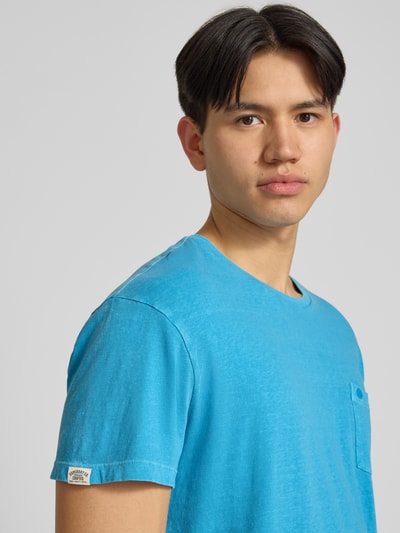 Männermodel trägt T-Shirt aus Baumwoll-Leinen-Mix mit Brusttasche von Superdry in Blau, Regular Fit, Nahaufnahme Oberkörper.