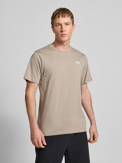 Mężczyzna model nosi T-shirt mit Label-Stitching von The North Face z mieszanki bawełny, krój regular fit, okrągły dekolt, długość tyłu 70 cm w rozmiarze M, kolor jasnobeżowy, gładka faktura, Ganzkörperansicht z przodu.