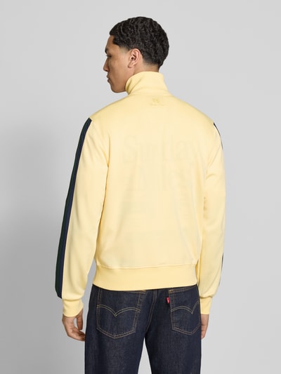 Männermodel trägt Regular Fit Sweatjacke mit Logo-Detail von ANOTHER COTTON LAB, gelb mit dunkelblauen Ärmeln, Stehkragen, Elastischer-Material-Mix, Rückenansicht Ganzkörperansicht.