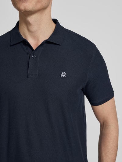 Męski model nosi Regular Fit Poloshirt mit Logo-Stitching Modell 'Performance' od Lerros z mieszanki bawełny, krótki rękaw, ciemnoniebieski, detal wyhaftowanego logo, długość tyłu w rozmiarze M: 72 cm, zbliżenie na górną część ciała