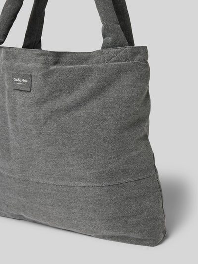 Produktfoto, Tote Bag aus reiner Baumwolle in Denim-Optik von Studio Noos in Dunkelgrau mit Logo-Detail, sichtbare grobe Gewebestruktur. Breite 60 cm, Länge 42 cm, Tiefe 9 cm, Schulterriemen 75 cm.