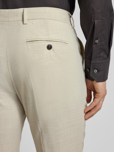 Męski model nosi Slim Fit Anzughose mit Woll-Anteil Modell 'SLIM-OASIS' von SELECTED HOMME, z efektem melanżu, krój slim fit, kanty, szlufki na pasek, zapięcie na guzik i zamek błyskawiczny, wpuszczane kieszenie, kieszeń z tyłu, wykończenie materiału: splot twill, kolor jasny beż, detailaufnahme tył.