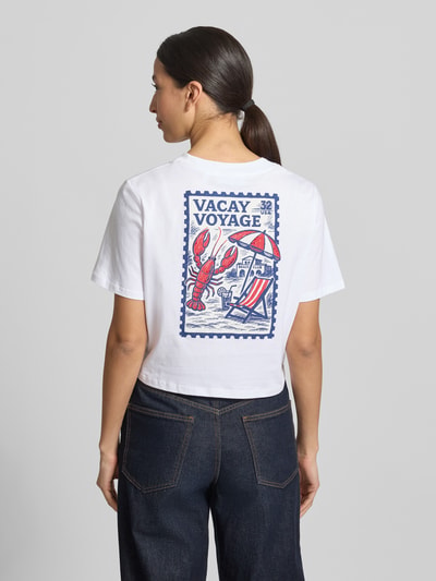 Frauenmodel trägt T-Shirt mit Knotendetail und Rundhalsausschnitt von Rich & Royal, reine Baumwolle, weiß mit buntem Print, Rückenlänge 44 cm, Ganzkörperansicht Rückansicht.
