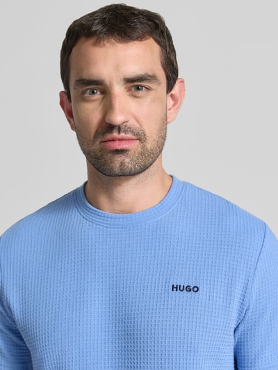 Männermodel trägt Herren T-Shirt aus Baumwoll-Mix Modell 'AUSTIN' von HUGO in Hellblau mit feiner Waffelstruktur, Nahaufnahme Oberkörper.