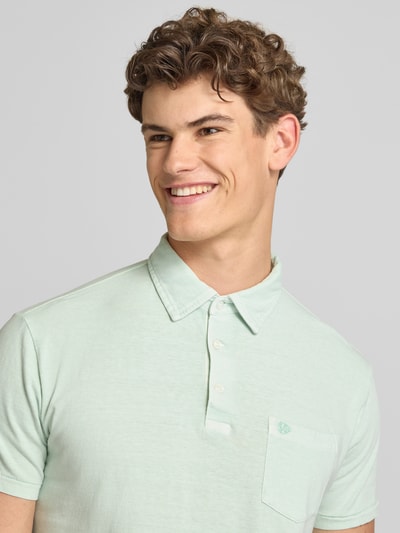 Männermodel trägt Slim Fit Poloshirt mit Brusttasche von Superdry, Baumwoll-Leinen-Mix, Knopfleiste, Rückenlänge 67 cm, Nahaufnahme Oberkörper.