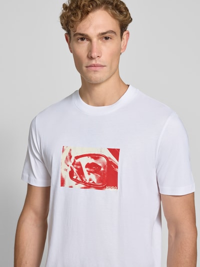Männermodel trägt Regular Fit T-Shirt aus reiner Baumwolle Modell 'Dirom' von HUGO in Weiß mit rotem Print, Nahaufnahme Oberkörper, Herren T-Shirt von HUGO.