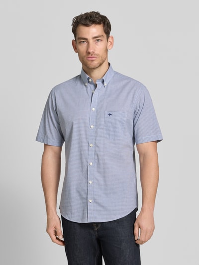 Männermodel trägt Modern Fit Freizeithemd mit Brusttasche und Logo-Stitching von Fynch-Hatton, Reine Baumwolle, Button-Down-Kragen, Knopfleiste, Kurzarm, dezentes Karo-Muster in Blau-Weiß, abgerundeter Saum, Ganzkörperansicht von vorne.