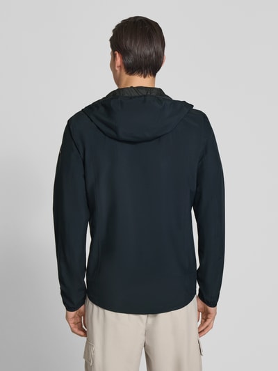 Männermodel trägt Regular Fit Jacke mit Kapuze von SCANDINAVIAN EDITION in Dunkelblau, glatte Struktur, Rückenansicht, Ganzkörperansicht Rückansicht. Herren Jacke mit Zweiwege-Reißverschluss, Eingrifftaschen mit Reißverschluss, Rückenlänge 76 cm, Schulterbreite 43 cm, Brustweite 42 cm, Ärmellänge 68 cm, Größe M.