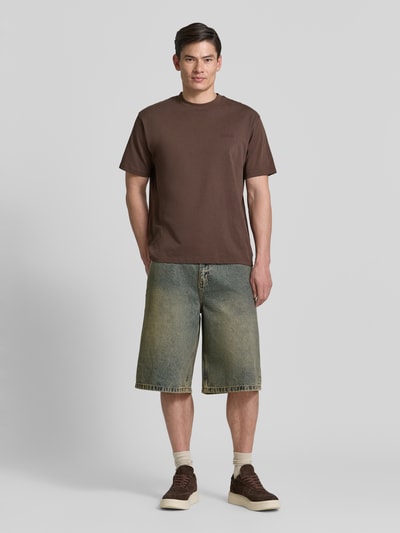 Männermodel trägt Jeansshorts mit Eingrifftaschen Modell 'Yuto Aged' von WOODBIRD aus reiner Baumwolle im Relaxed-Fit, Ganzkörperansicht von vorne.