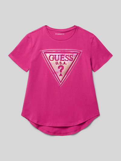Produktfoto, T-Shirt mit Strasssteinbesatz und Logo-Print von Guess, bawełniany mix z elastanem, luźny krój, okrągły dekolt, wydłużony tył, różowy kolor, długość tyłu w rozmiarze 140: 53 cm