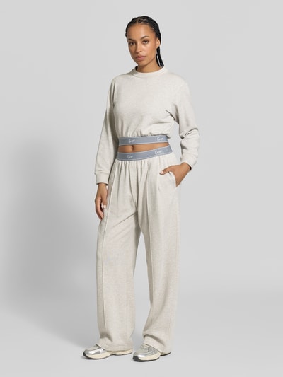 Frauenmodel trägt Wide Fit Sweatpants mit Logo-Stitching von Kenzo in Beige mit elastischem Bund und Frottee-Optik, Ganzkörperansicht von vorne.