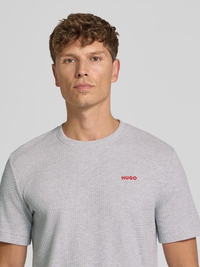 Männermodel trägt hellgraues Herren T-Shirt aus Baumwoll-Mix Modell 'AUSTIN' von HUGO mit feiner Struktur, Nahaufnahme Oberkörper.