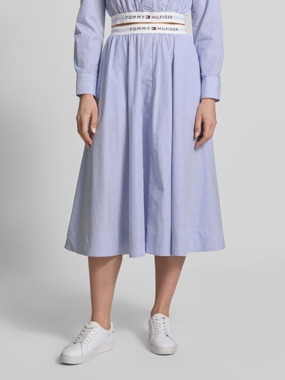 Frauenmodel trägt Ausgestellter Midi-Rock aus reiner Baumwolle von Tommy Hilfiger, efekt: wzór w paski, krój regular fit, rozkloszowana, długość midi, wzór w paski, z napisem z logo, elastyczny ściągacz, wykończenie materiału: drobno tkana faktura, materiał: bawełna, Ganzkörperansicht von vorne.