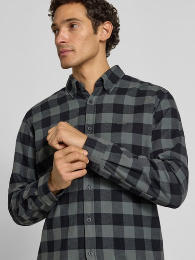 Männermodel trägt Regular Fit Freizeithemd aus reiner Baumwolle Modell 'Rickert_M' von BOSS, kariertes Muster in Schwarz und Grau, Nahaufnahme Oberkörper, Herren Freizeithemd von BOSS Orange.