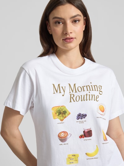 Frauenmodel trägt T-Shirt mit Motiv-Print Modell 'COLLAGE' von JJXX aus reiner Baumwolle, weiß, entspannte Passform, Nahaufnahme Oberkörper.