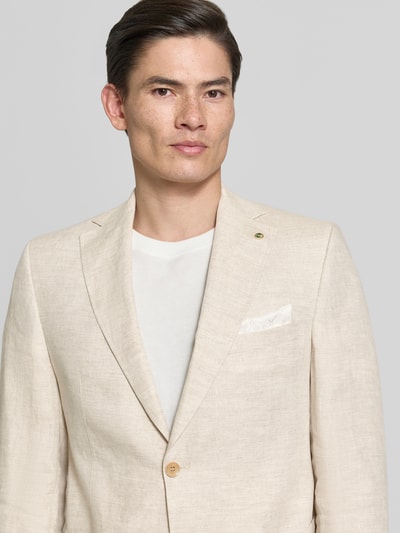 Męski model nosi Regular Fit Sakko aus Leinen-Mix Modell 'Tebbo' od Carl Gross, jasnobeżowy, tekstura lnu, krój regular fit, tkanina czysta len, kieszeń na piersi, naszywane kieszenie, kołnierz z klapami, zapięcie na dwa guziki, długość tyłu w rozmiarze 50: 75 cm, szerokość w rozmiarze 50: 43 cm, długość rękawa w rozmiarze 50: 65 cm, zdjęcie z przodu, zbliżenie na górną część ciała.