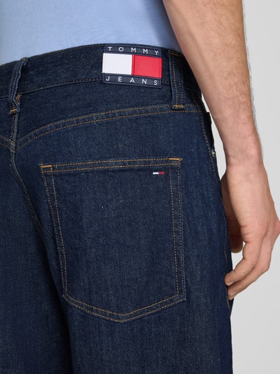 Männermodel trägt Barrel fit Jeans aus Baumwoll-Mix Modell 'ASHTON' von Tommy Jeans, dunkelblauer Stoff, Detailaufnahme, Herren Barrel Jeans von Tommy Jeans.