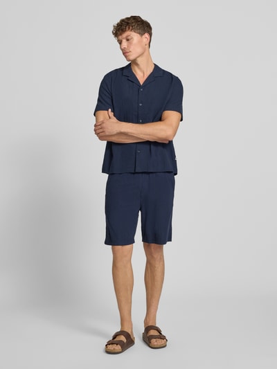 Männermodel trägt Resort Fit Freizeithemd aus reiner Baumwolle von s.Oliver RED LABEL in Dunkelblau, lockere Form, Ganzkörperansicht von vorne.