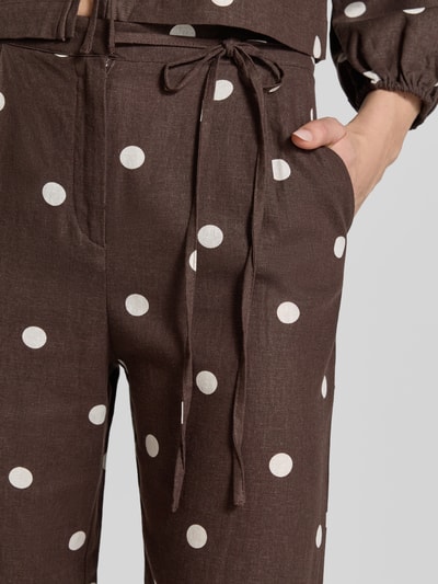 Frauenmodel trägt Stoffhose mit Schleifen-Detail von Jake*s Casual, braun mit weißen Punkten, Lockerer-Schnitt, Nahaufnahme Oberkörper. Bundweite 40 cm, Innenbeinlänge 83 cm bei Größe 36.