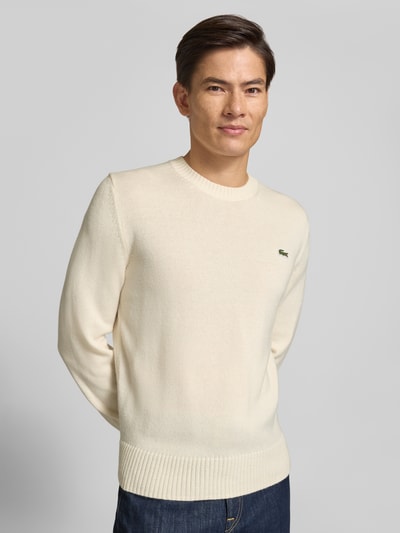 Männermodel trägt Regular Fit Pullover aus reiner Wolle von Lacoste in creme, glatte Strickstruktur, Nahaufnahme Oberkörper, Herren Pullover von Lacoste.