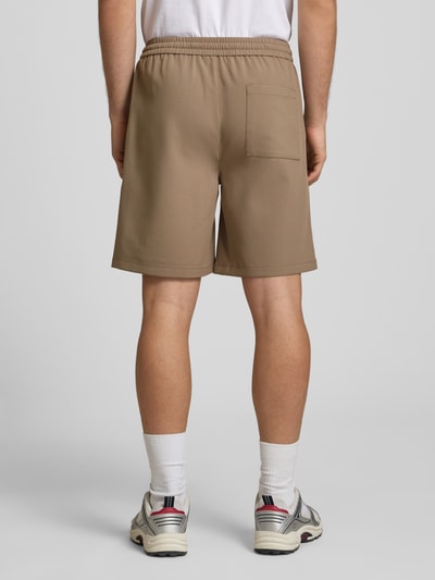 Männermodel trägt Loose Fit Shorts mit elastischem Bund Modell 'WILL' van Only & Sons, effen, met bandplooi, elastische taille met trekkoord, steekzakken, achterzak, bruin, Ganzkörperansicht Rückansicht.