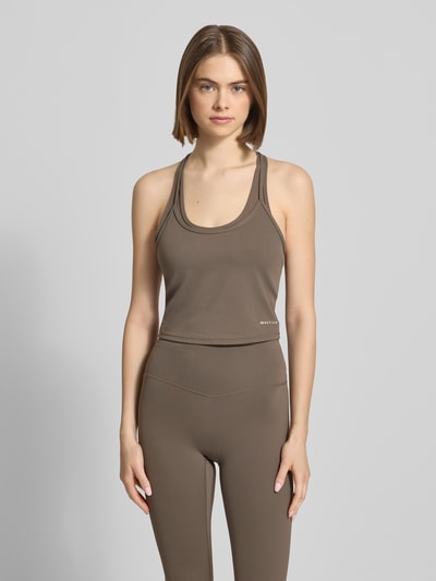 Modelka kobieca nosi Double Layer Tanktop mit Logo od P.E Nation w kolorze brązowym, materiał z domieszką stretchu, długość pleców w rozmiarze S: 55 cm, widok całej sylwetki z przodu.