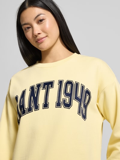 Frauenmodel trägt Sweatshirt mit Label-Print und Rundhalsausschnitt von Gant in Gelb aus reiner Baumwolle, Relaxed-Fit, Nahaufnahme Oberkörper.