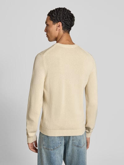 Männermodel trägt Strickpullover mit gerippten Abschlüssen von REVIEW in Beige, reine Baumwolle, gerader Schnitt, Ganzkörperansicht Rückansicht.