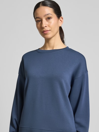 Kobiece model prezentuje bluzę z mieszanki wiskozy z dodatkiem streczu, luźny krój, okrągły dekolt, model 'Ima Q' od MSCH Copenhagen, damska bluza, miękka faktura, gładki granatowy materiał, wyraźne przeszycia, widoczne obniżone ramiona, zbliżenie na górną część ciała, zdjęcie z przodu
