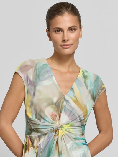 Frauenmodel trägt Minikleid mit V-Ausschnitt und Knotendetail von Betty Barclay, Allover-Look, Material-Mix mit Stretch-Anteil, Nahaufnahme Oberkörper.
