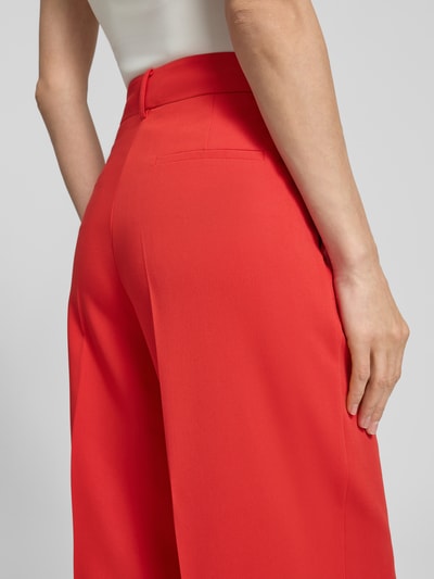 Frauenmodel trägt Hose mit Bügelfalten von More & More, leuchtend rot, Material-Mix mit Viskose-Anteil, Gesäßtaschen, Nahaufnahme Rückansicht.