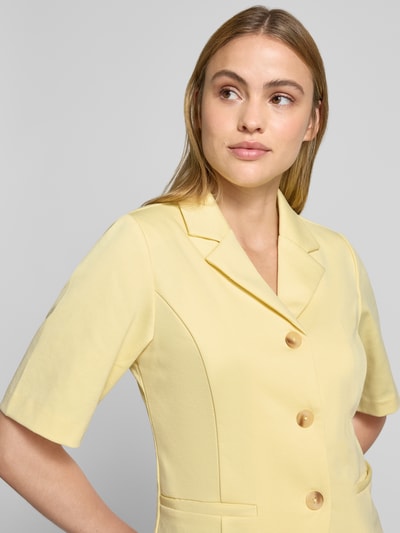 Frauenmodel trägt Blazer mit Viskose-Anteil Modell 'Kate' von ICHI in zartem Gelb mit Reverskragen, Halbarm, durchgehender Knopfleiste, Paspeltaschen; Elastischer-Material-Mix, Taillierte Passform, Nahaufnahme Oberkörper.