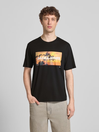 Männermodel trägt T-Shirt mit Label-Print Modell 'INDIANA' von Jack & Jones, schwarze Baumwolle, Regular Fit, Rundhalsausschnitt, Ganzkörperansicht von vorne.