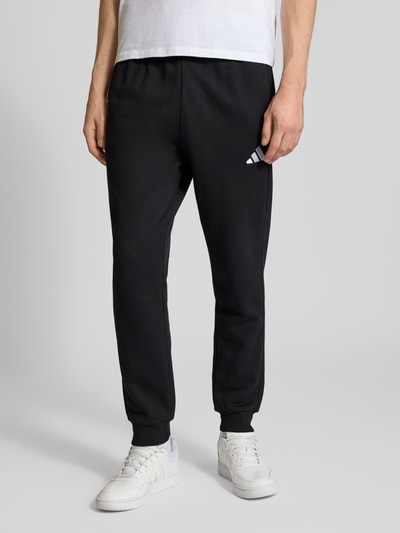 Männermodel trägt Regular Fit Sweat-Anzug aus Baumwoll-Mix von adidas Sportswear, Optik: Unifarben, Nahaufnahme Unterkörper.
