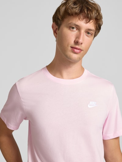 Männermodel trägt Regular Fit T-Shirt aus reiner Baumwolle von Nike in Rosa mit glatter Textur, Nahaufnahme Oberkörper.